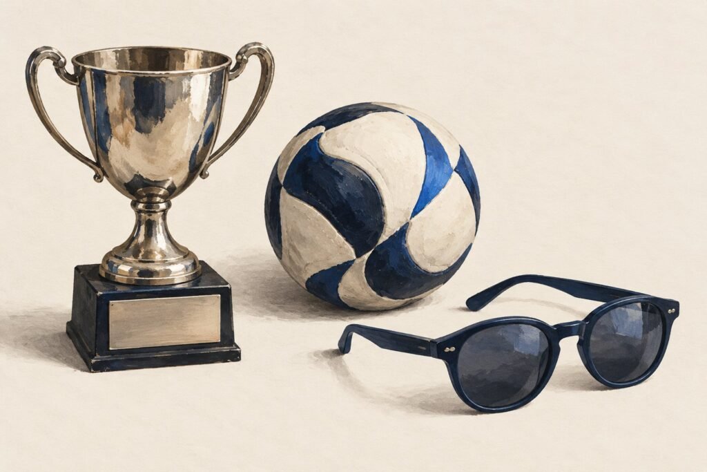 Une coupe à plaque vierge, un ballon bleu et blanc et une paire de lunettes de soleil, sur un fond clair
